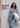 mobile alternative for Woman wearing a striped shirt and pants with a white bag, text 'Mother's Day Gifts She'll Actually Wear' on a wooden surface.