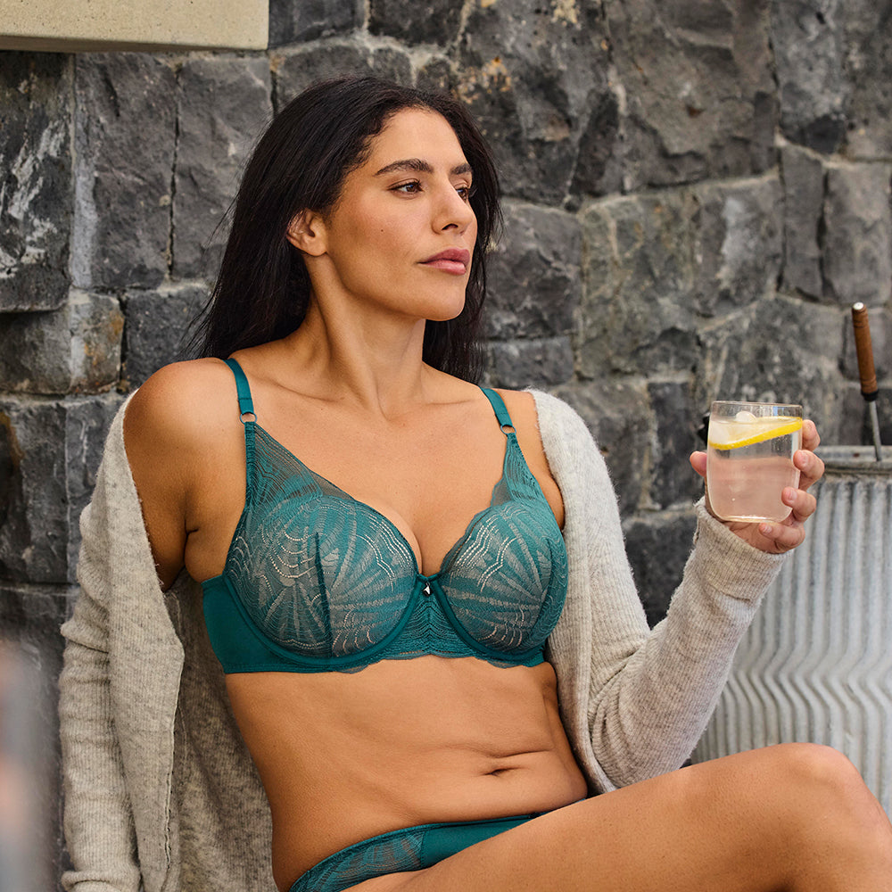 model poses with glass of water wearing green lingerie set