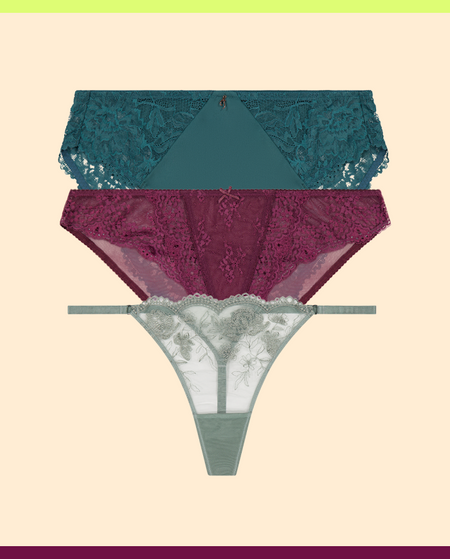 Three pairs of lace underwear in teal, purple, and gray on a beige background.