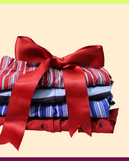 Stack of folded clothes with a red ribbon on a beige background