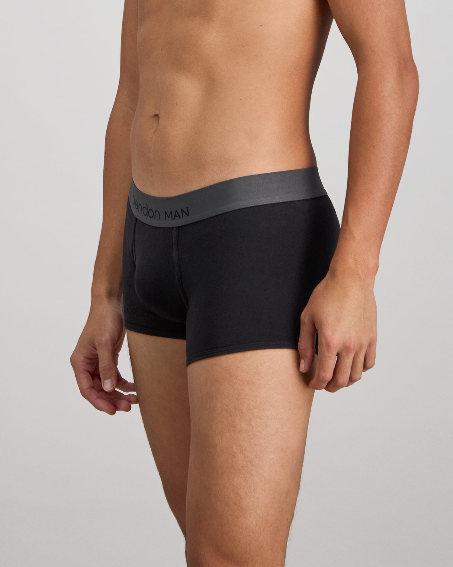 Model wears Cotton Low-Rise Mens Trunk in BLACK. On body side view