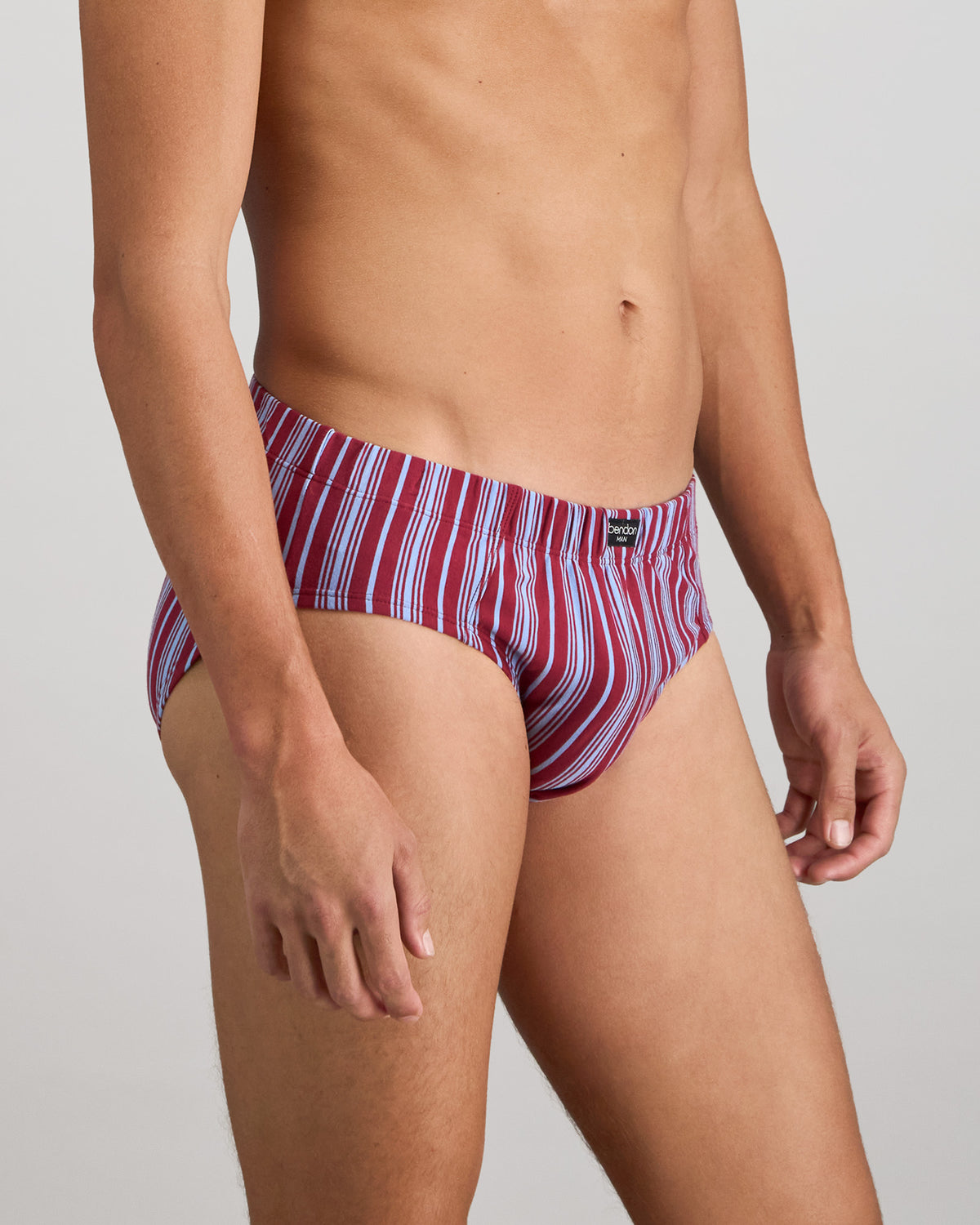 Model wears Cotton Stretch Mens Brief in TIBETAN RED STRIPE. On body side view