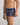 Model wears Retros Print Mens Trunk in GOLD TROPICAL PRINT. On body side view