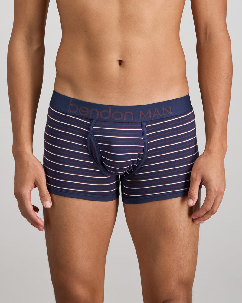 Model wears Bold Stripe Mens Trunk in PEACOAT/PLUM STRIPE. On body front view