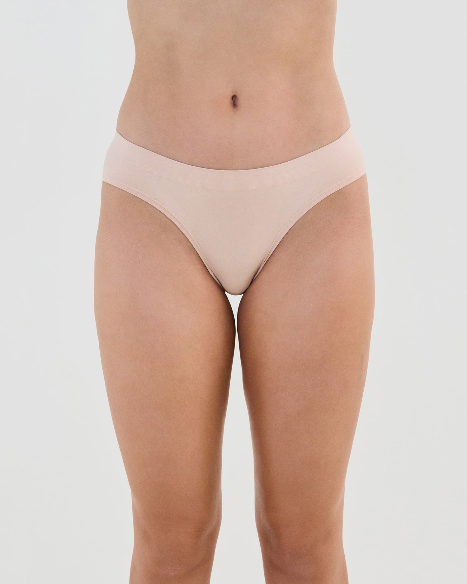 Model wears Seamless Soft Bikini in LATTE. On body front view