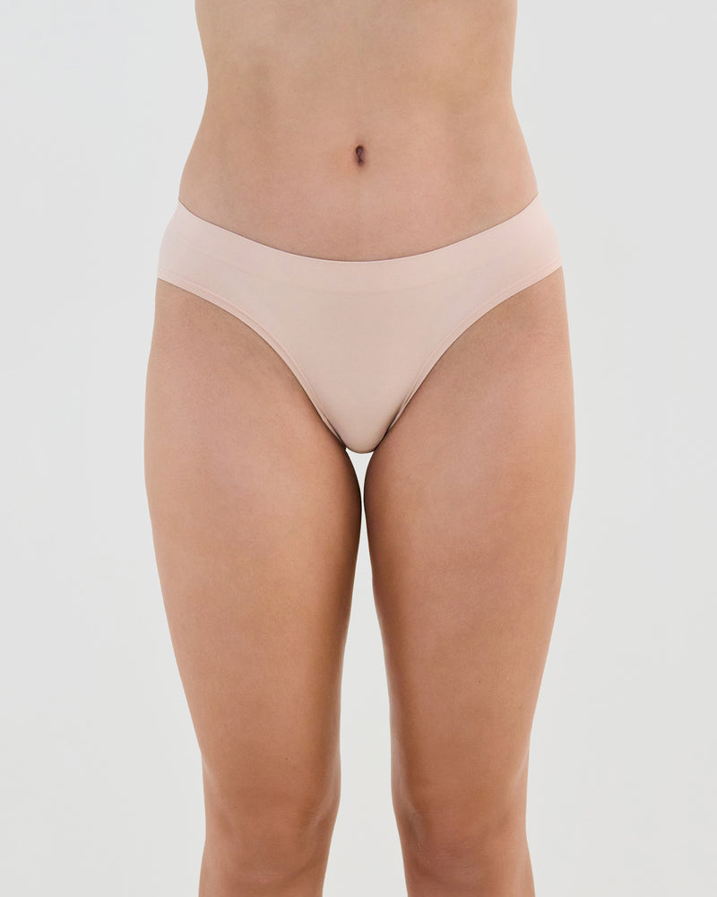 Model wears Seamless Soft Bikini in LATTE. On body front view