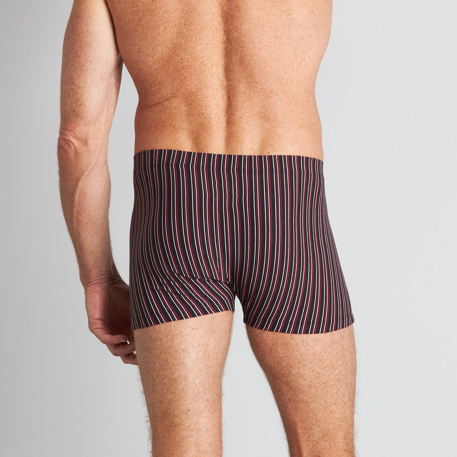 Model wears Cotton Stretch Mens Trunk in BLACK/RHUBARB STRIPE. On body back view