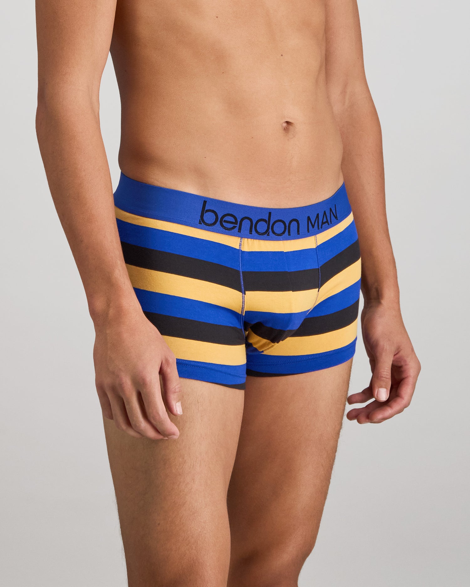Model wears Rugby Stripe Mens Trunk in BLACK/SURF/OAK BUFF. On body side view