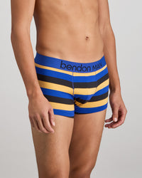 Model wears Rugby Stripe Mens Trunk in BLACK/SURF/OAK BUFF. On body side view