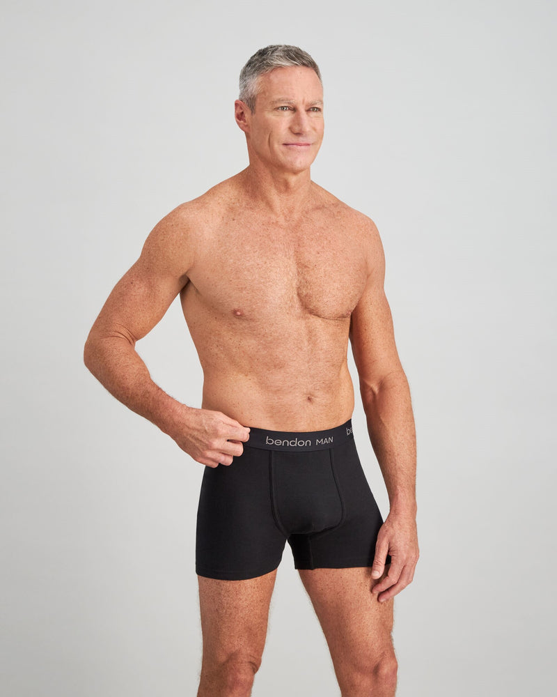 Model wears Cotton Classics Mens Trunk in BLACK. On body side view