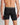 Model wears Everyday Active Mens Long Trunk in BLACK. On body back view