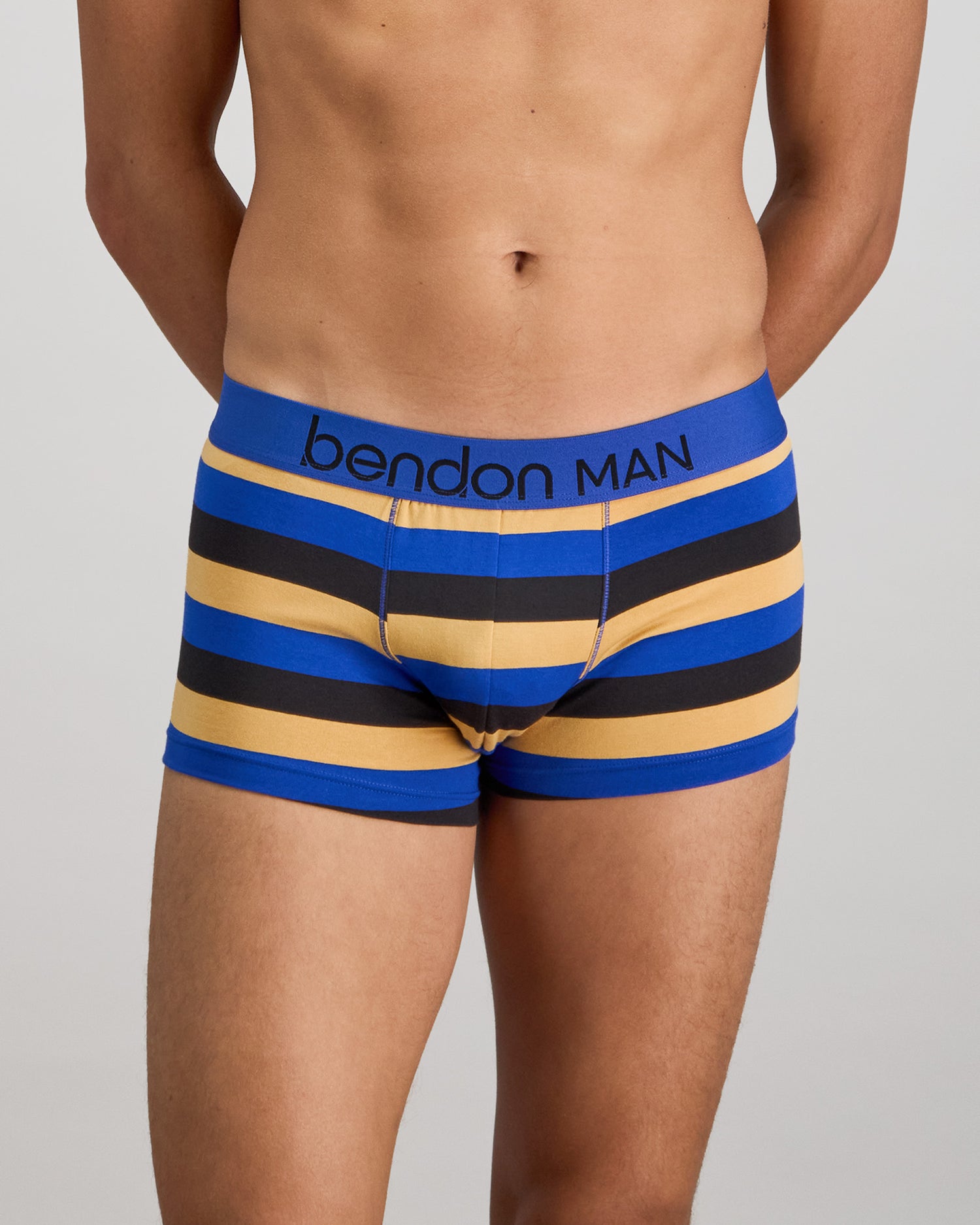 Model wears Rugby Stripe Mens Trunk in BLACK/SURF/OAK BUFF. On body front view
