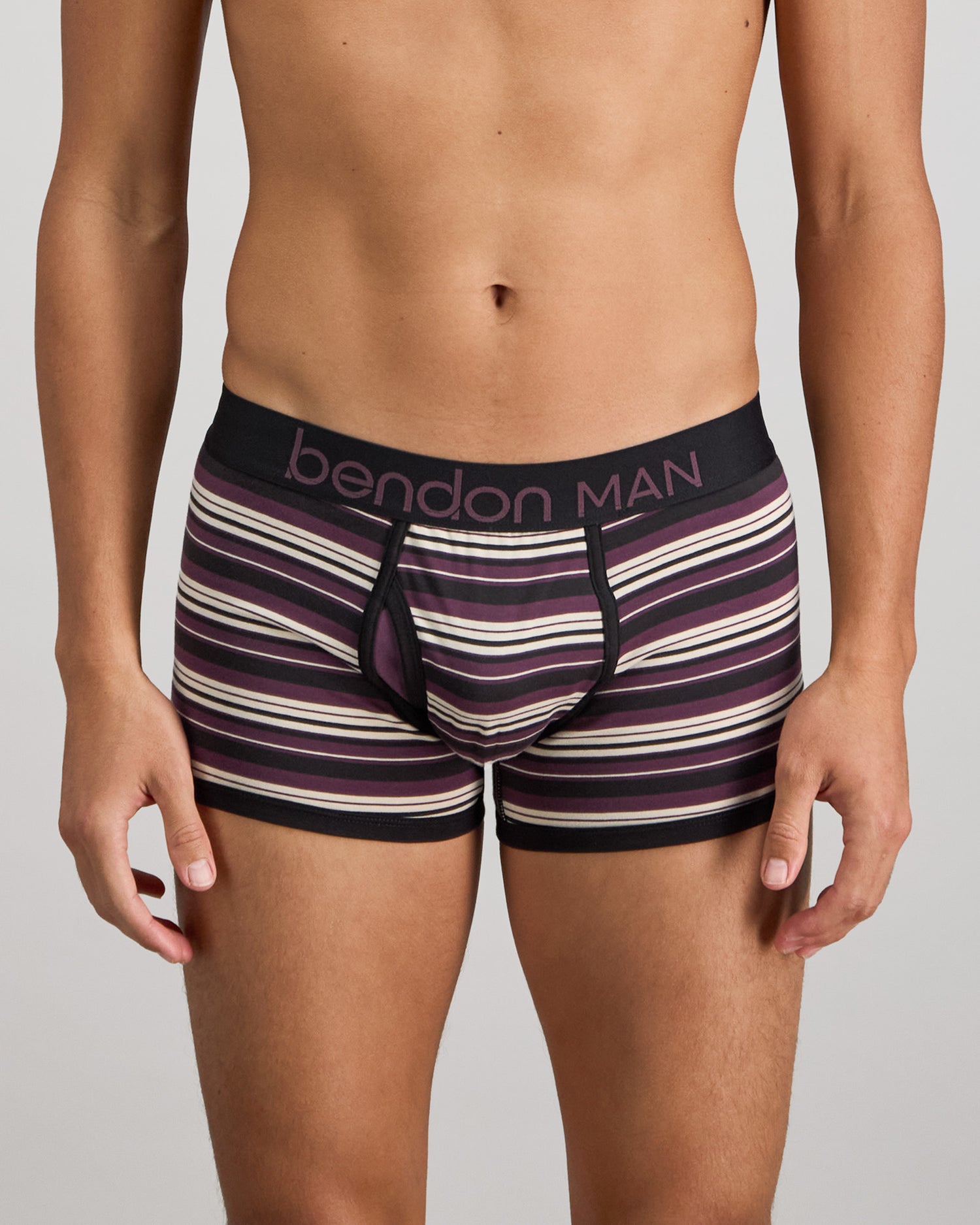 Model wears Bold Stripe Mens Trunk in BLACK/PLUM STRIPE. On body front view