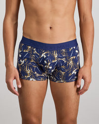 Model wears Retros Print Mens Trunk in GOLD TROPICAL PRINT. On body front view