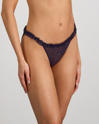 Model wears Wrapped In Stardust Tanga in PURPLE VELVET. On body side view