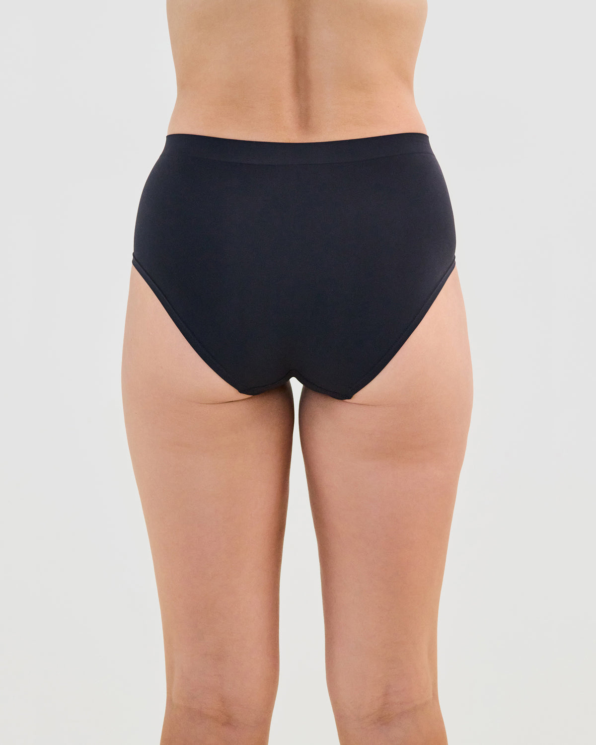 Model wears Seamless Soft Full Brief in BLACK. On body back view