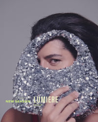 model-poses-wearing-red-bra-holding-silver-bag-above-head