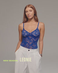 model-poses-in-blue-lacey-bodysuit-and-white-pants